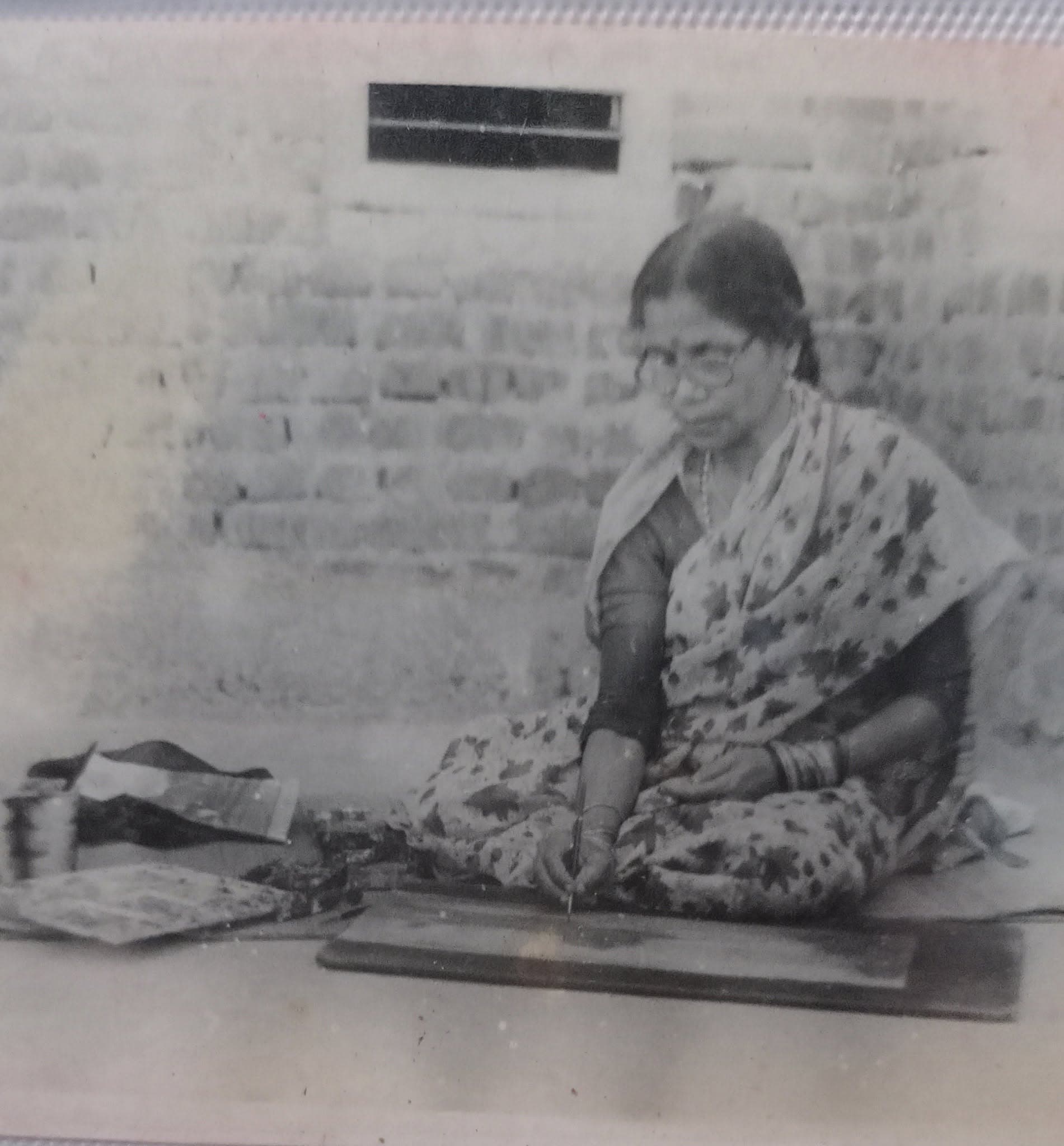Archival black and white photograph of Basanta Kumari Samanta seated on the floor at work in her early years