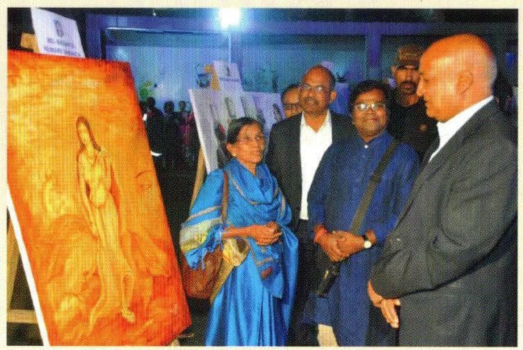 Basanta Kumari Samanta walking a group of visitors past her paintings at an evening exhibition