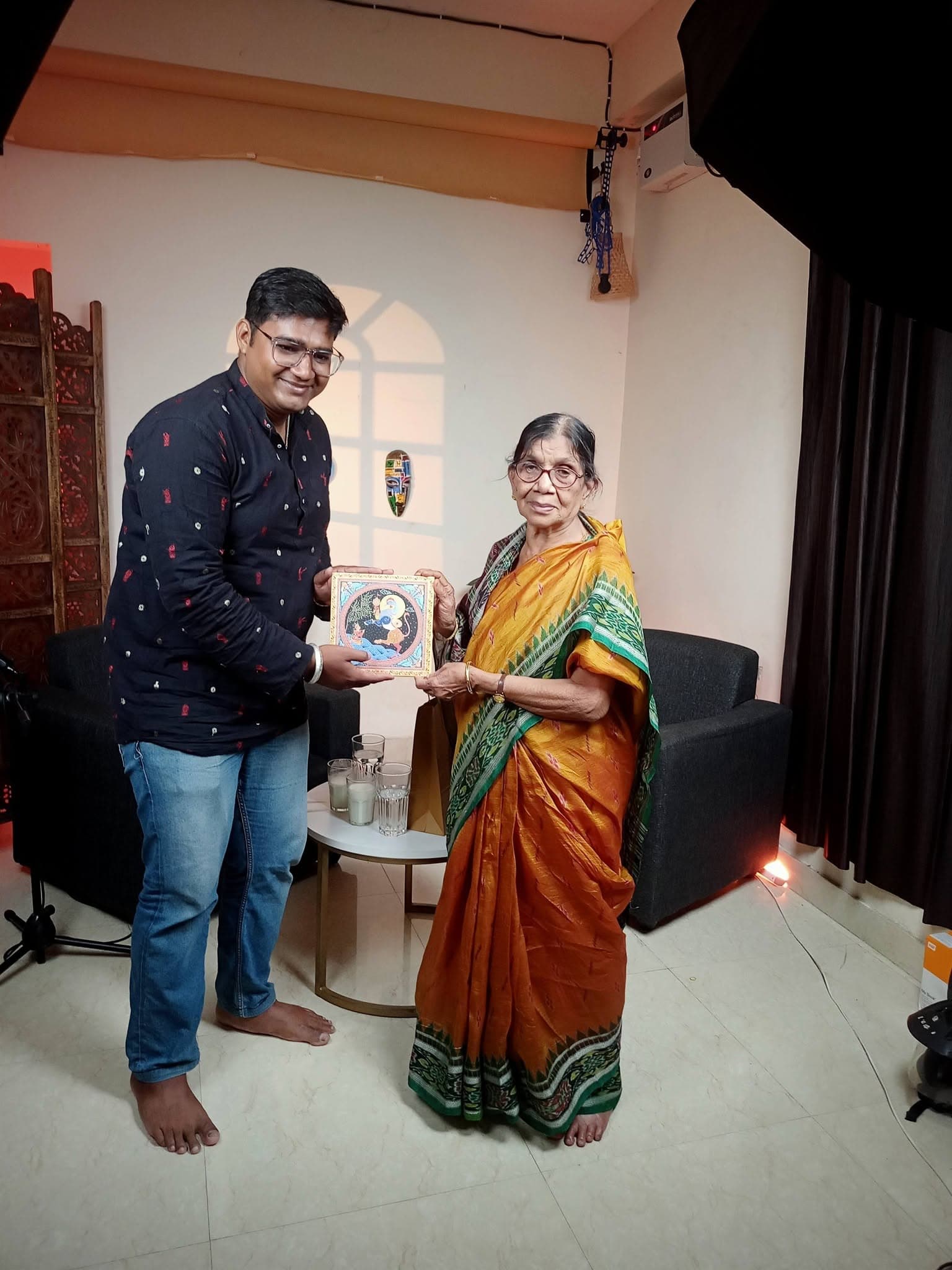 Basanta Kumari Samanta being presented with a hand-painted patachitra artwork on an interview set