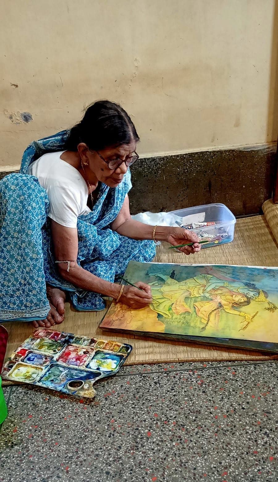 Basanta Kumari Samanta seated on the floor painting a Radha Krishna themed watercolour artwork