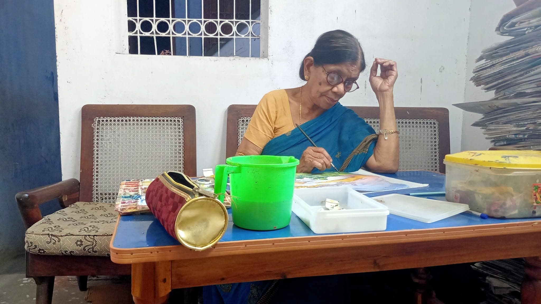 Basanta Kumari Samanta at work on a watercolour painting at her home worktable