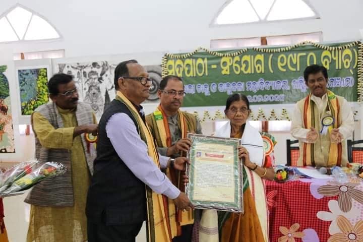 Basanta Kumari Samanta receiving a framed citation from fellow honourees at a felicitation programme